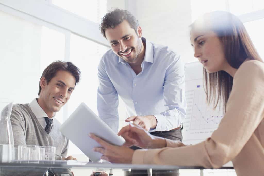 Smiling business people using digital tablet in meeting
